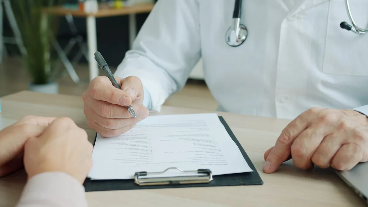 Médico comentando un informe médico con un paciente en la consulta